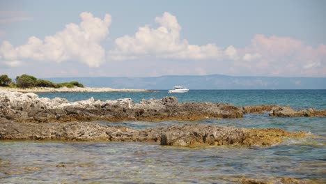 A-white-power-boat-is-anchored-just-off-a-coastline-on-blue-water