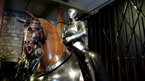 slow rotating shot of a metal knight on the back of a horse in the tower of london