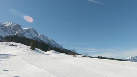 panoramic shot taken from a ski lift moving uphill with skiers, in the background a panorama of snowy mountain peaks