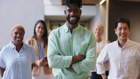 smiling team of diverse professionals standing together in modern office hallway