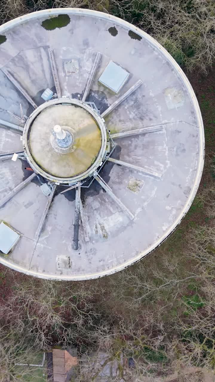 Voo vertical de drone aéreo da torre de água de Bengeo, de cima para baixo, começando acima dos telhados do bairro, depois revelando árvores ao redor da torre, terminando sobre casas, quintais e jardins próximos