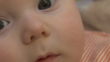 Close-up-of-a-sweet-baby-gazing-up-at-the-camera-and-then-smiling