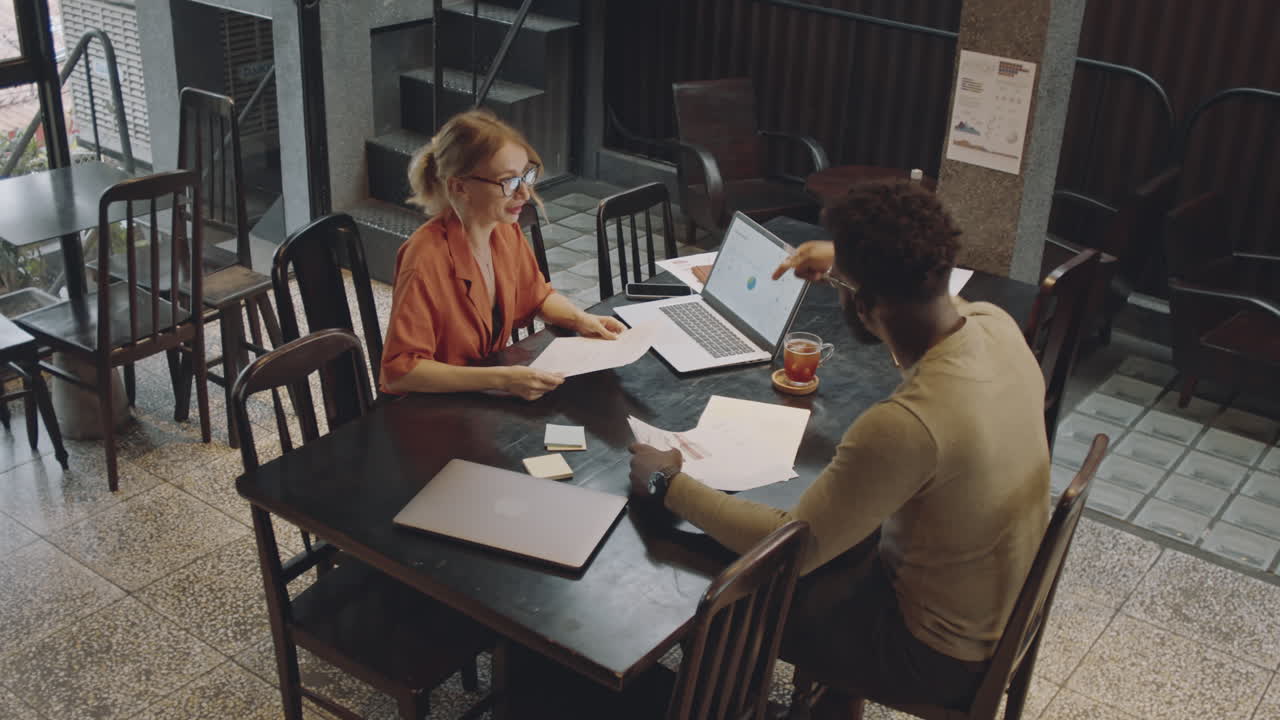 Multiethnic Business Partners Discussing Project in Cafe