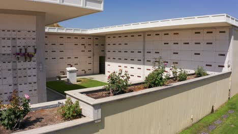 Low-aerial-dolly-shot-along-a-flower-garden-in-front-of-a-stone-mausoleum-at-a-California-mortuary