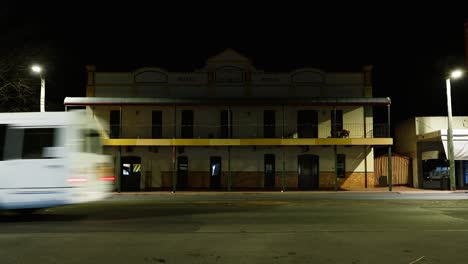 vehicles passing by an old, illuminated building at night