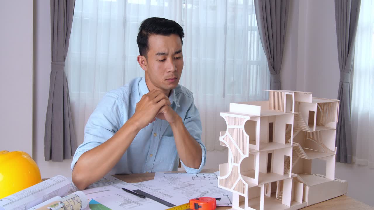 Young Architect Working On House Model. Male Designer At His Workdesk Thinking About New Architectural Ideas