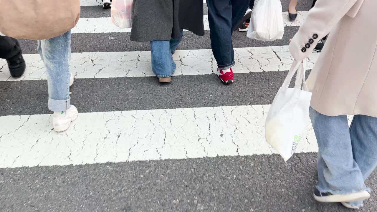 도시 거리의 흰색 지브라 횡단보도를 건너는 사람들의 로우 앵글 샷.