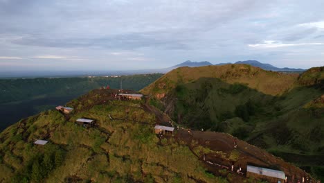 tourists-in-huts-during-sunrise-golden-hour-at-Mount-Batur-volcano-in-Bali-Indonesia,-aerial