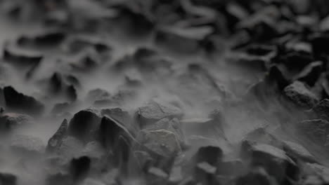 Close-up-Macro-Shot-Of-White-Mist-Slowly-Settling-Over-Black-Stones