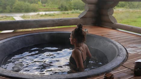 woman relaxing in a wooden hot tub with nature view