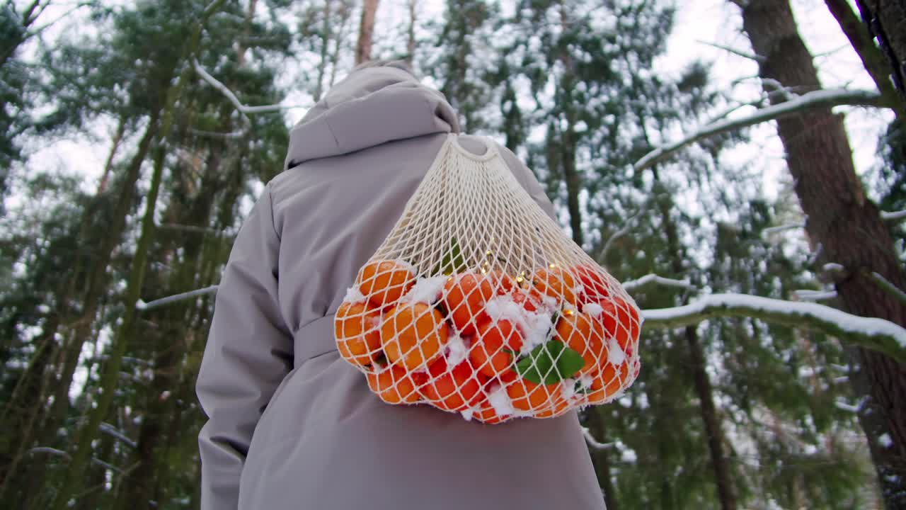 눈 인 숲 에서 망 가방 에 오렌지 를 들고 있는 여자