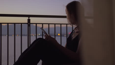 Woman-using-smart-phone-on-the-balcony-overlooking-sea