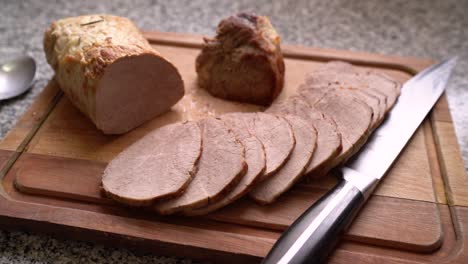 meat slices cooked in the oven with knife on wooden chopping board