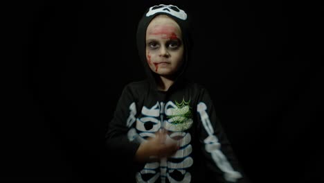 halloween angry girl with blood makeup on face. kid dressed as scary skeleton, dancing, making faces