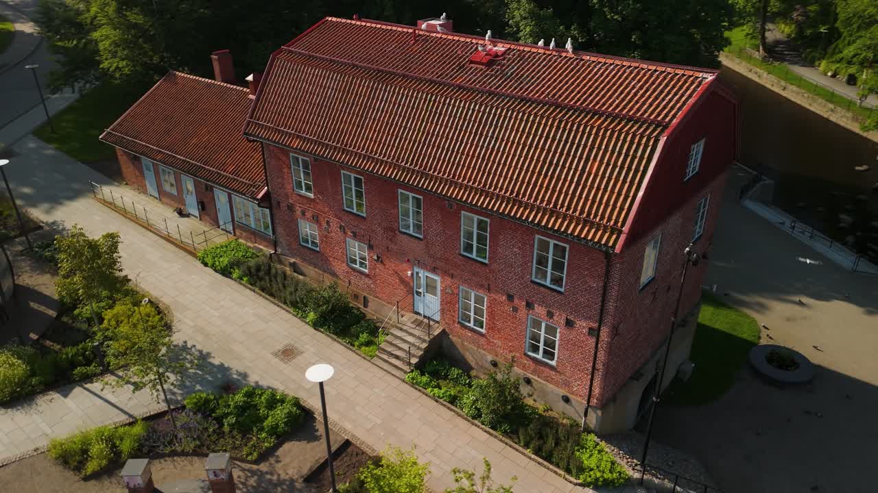 Luftbåren parallax droneoptagelse, der kredser om Hasselbackshuset, en historisk hollandsk murstensbygning fra det tidlige 19. århundrede med rødt tegltag nær Kungstorget i Uddevalla, Sverige