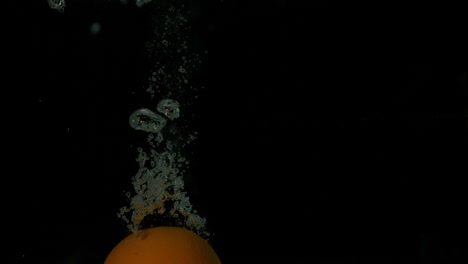 Orange-plunging-into-water-on-black-background