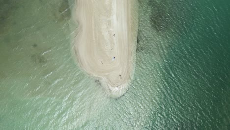 descending aerial view of a bikini model laying in the white sand beach of no man land, tobago