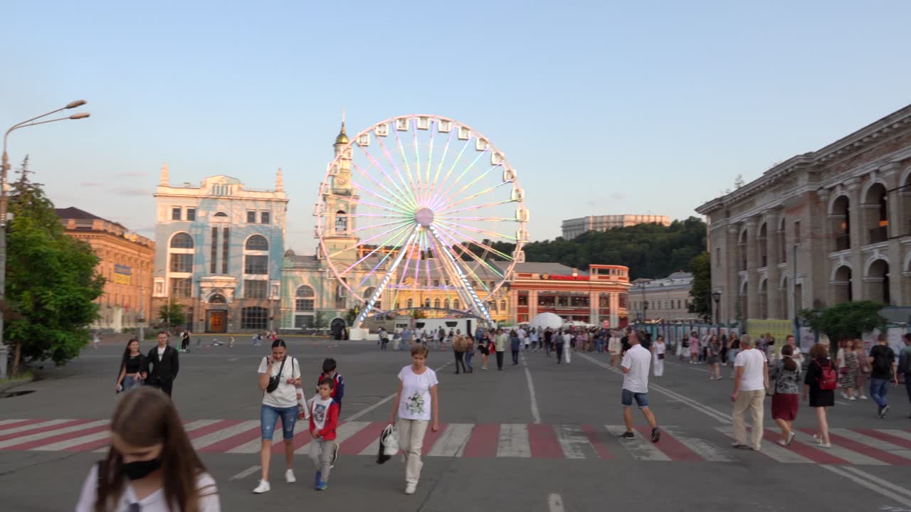 Ukraine,Kyiv,Kontraktova Square on a sunny day with blue skies.Beautiful old building by the side and the Observation wheel at the back and people walking in front of it,such a relax day in the square