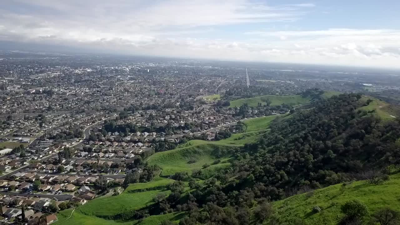 푸른 산기슭 근처의 고속도로와 교외 및 산업 스프롤의 조감도