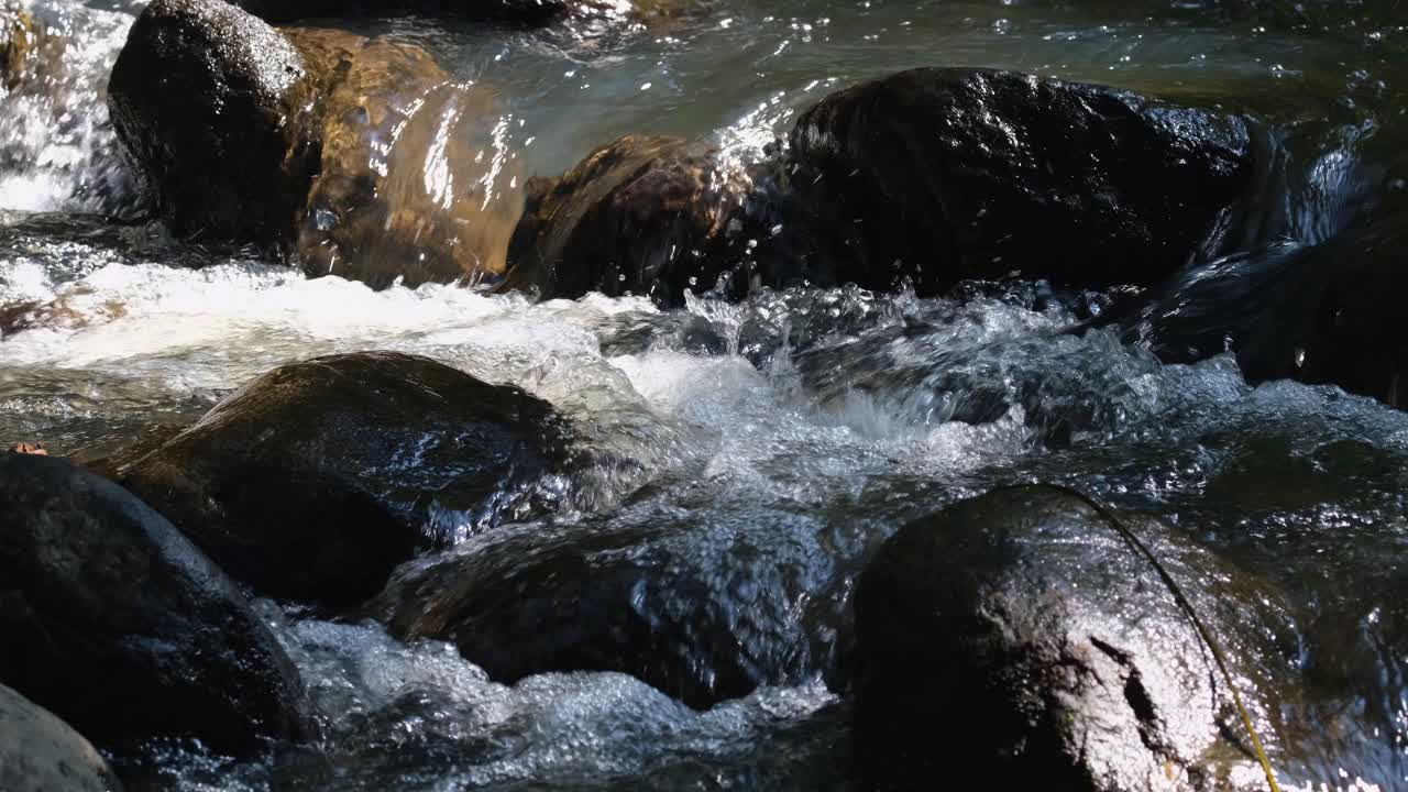 Fiume che scorre tra le rocce producendo suoni d'acqua e bolle di spuma.