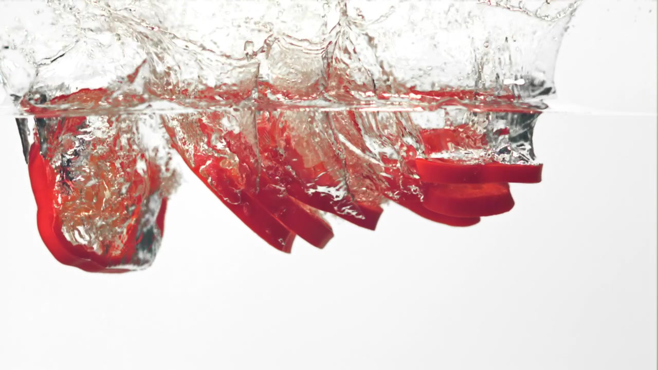 Red Bell Pepper Slices Falling and Splashing into Water in Slow Motion