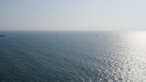 Varios-Windsurfistas-Con-Velas-Rojas-Navegan-Por-El-Claro-Mar-Mediterráneo-Que-Refleja-La-Luz-Del-Sol-Cerca-De-Herzeliya-En-Israel