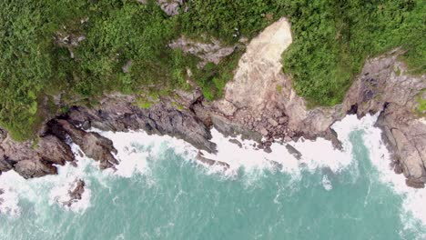 Aerial-view-of-a-jagged-rock-island,-surrounded-with-lush-green-nature-and-Hong-Kong-bay-water