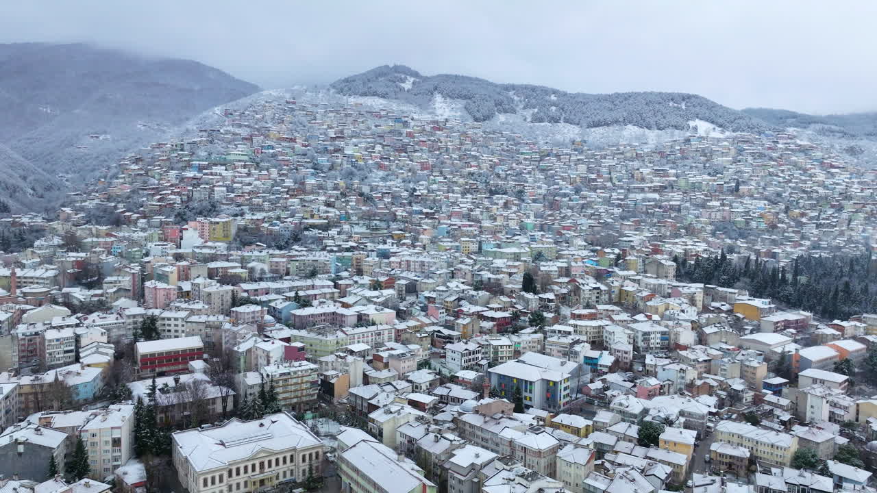 Türkiye'de taze kar altındaki Bursa şehir silüetinin yoğun yapılarının panoramik havadan görünümü.