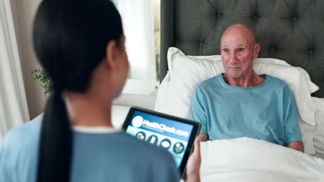 nurse using tablet to check on elderly patient in bed