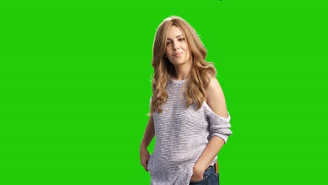 Attractive-cheerful-blonde-woman-posing-on-green-screen-and-adjusting-her-long-hair