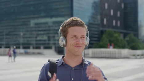 portrait attractive young man smiling listening to music takes off headphones in city enjoying relaxed urban lifestyle on sunny day slow motion leisure entertainment