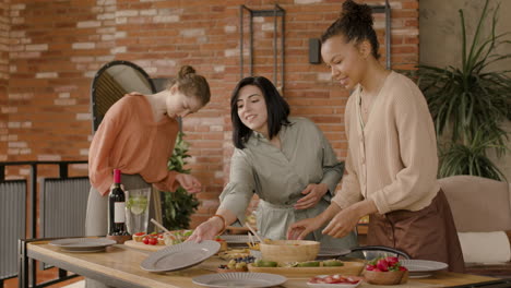 a friendly multicultural group of three women set the table for a gathering of friends