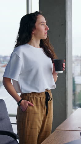 woman drinking coffee at office window