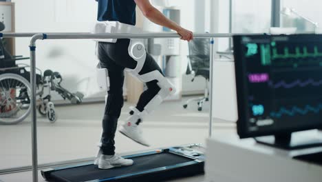 modern hospital physical therapy: patient with injury walks on treadmill wearing advanced robotic exoskeleton legs. physiotherapy rehabilitation technology to make disabled person walk. focus on legs