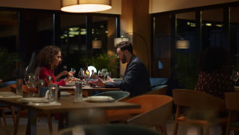 una pareja sonriente sentada en un restaurante por la noche. dos personas de raza mixta hablan en un café.