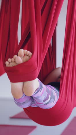 tired ladies lie with bare feet in long bright aerial fly yoga hammocks after advanced lesson in modern gym close view