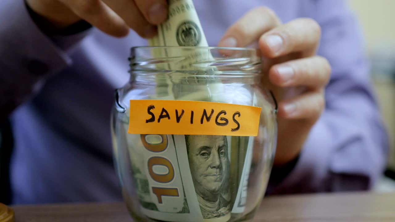 Caucasian man putting a glass jar put in a drawer table with his savings for future saving