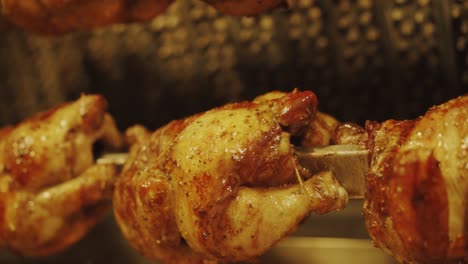 pollos enteros a la parrilla con una sabrosa piel asada de color amarillo dorado en un asador giratorio seguido - cierre, cámara lenta