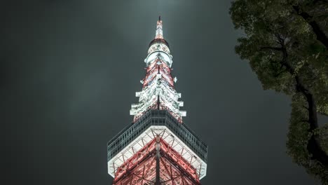 low angle timelapse of tokyo tower against the cloudy night sky