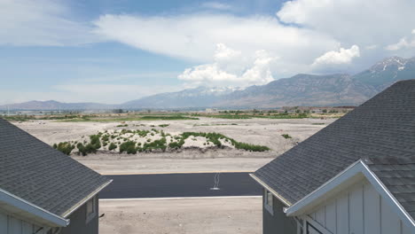 Aerial-view-flying-between-new-build-suburban-houses-to-reveal-property-development-land-and-Utah-mountain-landscape