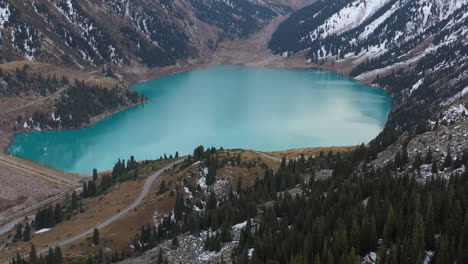 cinematic revealing drone footage of the big almaty lake starting on the forest then tilting up, in the trans-ili alatau mountains in kazakhstan