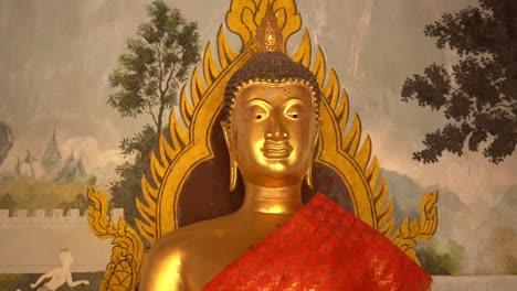close up on the head of a golden buddha statue with tradicional paintings on the background. chiang mai, thailand.