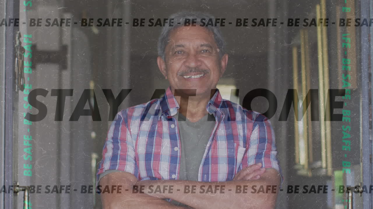 Animation of stay at home be safe text over senior man smiling at home