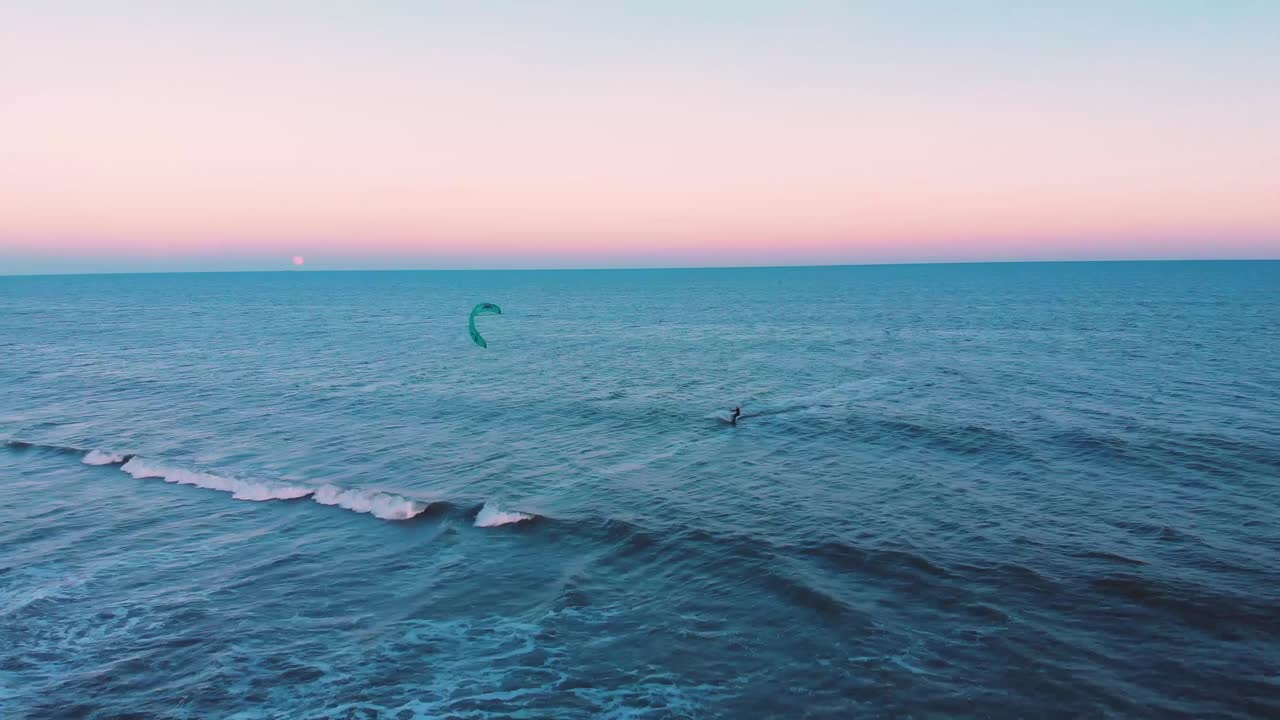 kitesurf solo en el amplio océano azul durante la colorida y pacífica puesta de sol