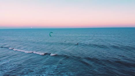 kitesurfing alone in blue wide ocean during colorful peaceful sunset