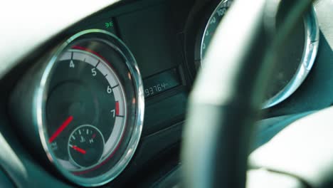 a young man points his index finger at rental car work vehicle dashboard instrument gauge cluster digital odometer mileage reading