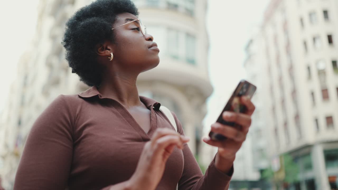 Dark-skinned woman using phone outdoors