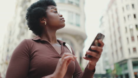 dark-skinned woman using phone outdoors