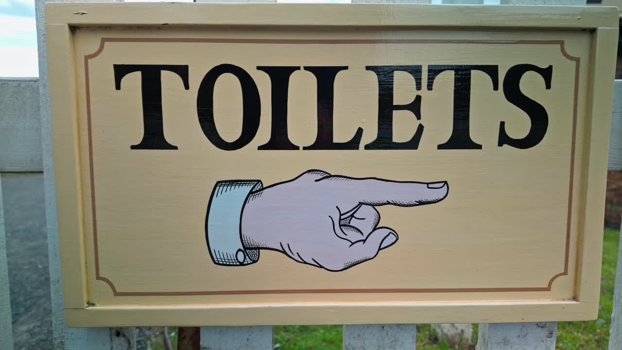 Pointing finger retro signboard informs public toilets restroom direction