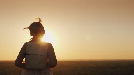 a young woman with a backpack runs forward towards the sun hair glows in the rays of sunset slow mot